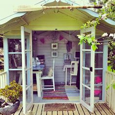 a small white shed sitting on top of a wooden deck