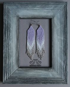 two pairs of beaded earrings are displayed in a shadow box with the word namitany on it