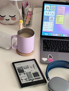 an open laptop computer sitting on top of a desk next to a cup of coffee