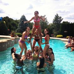 a group of women in bikinis standing around a pool