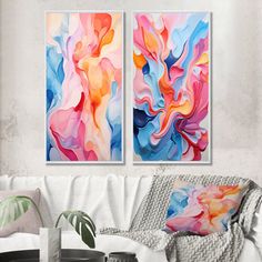 two paintings are hanging on the wall in a living room with white furniture and pillows