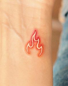 a small tattoo on the wrist of a woman's left arm with a red flame