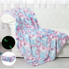 a couch covered in a pink and blue tie dye blanket next to a white chair