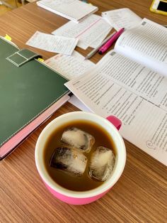 a cup of tea sitting on top of a wooden table next to an open book