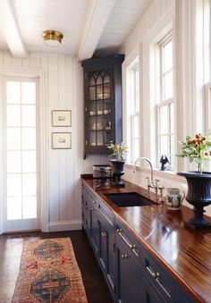 a kitchen with wooden counter tops and blue cabinetry, along with a rug on the floor