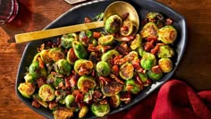 brussel sprouts with bacon in a serving dish next to a glass of wine