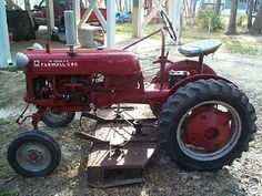 an old red farmall tractor sitting in the grass