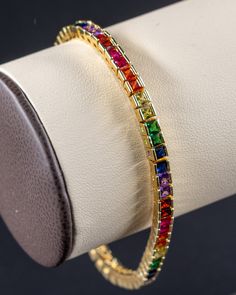 A timeless essential in fashion, the 4mm Multicolor Tennis Chain is the perfect accessory to add to your wrist. The bright multicolored stones, handset in an 18K Yellow Gold band are sure to turn some heads at any function. We stand by the quality and craftsmanship of our merchandise. All of our products are plated with high quality 14-18 karat gold, and if applicable, feature handset stones.  Our 4mm Multicolor Tennis Bracelets are 5 times PVD plated with 18K Yellow Gold, to ensure there's no fading, and feature handset AAAAA Multicolor CZ stones for a bold color that's sure to turn some heads. Material: Stainless Steel Finish: 18K Gold Stone: AAAAA Multicolor Cubic Zirconia Multicolor Cubic Zirconia Tennis Bracelet Gift, Elegant Multicolor Jewelry For Birthday, Elegant Multicolor Jewelry For Birthdays, Multicolor Multi-stone Tennis Bracelet As Gift, Multicolor Gemstone Tennis Bracelet As A Gift, Multicolor Gemstone Tennis Bracelet As Gift, Multicolor Bangle Bracelets For Anniversary, Rainbow Cubic Zirconia Bracelets For Gift, Rainbow Cubic Zirconia Bracelets As Gift