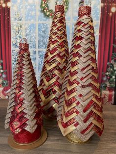 three red and gold christmas trees sitting next to each other on top of a wooden table