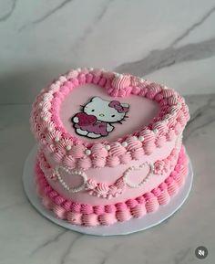 a hello kitty cake with pink icing and white frosting on the top is shaped like a heart