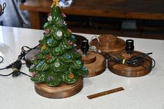 a ceramic christmas tree sitting on top of a wooden stand next to other ornaments and wires