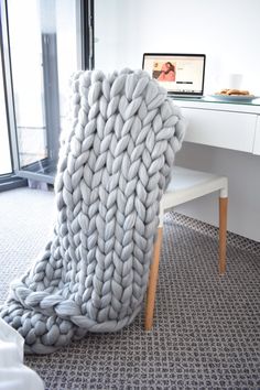 a large chunky blanket sitting on top of a white table next to a computer