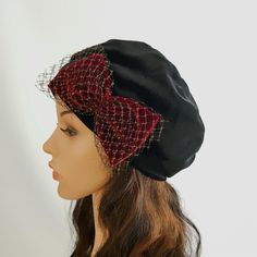 a mannequin head wearing a black and red hat with netting on the top