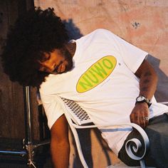 a young man sitting on top of a chair next to a wall with the word uno written on it