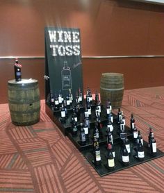 a table topped with bottles of wine on top of a wooden barrel next to a sign