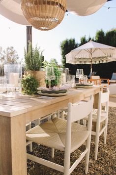 an outdoor dining table with chairs and umbrellas