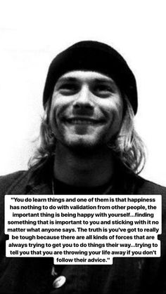 a man with long hair wearing a beanie smiles at the camera and says, you do learn things and one of them is that happiness