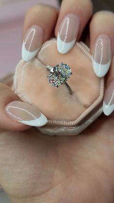 a woman's hand holding a diamond ring