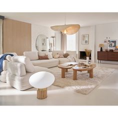 a living room filled with white furniture and a large mirror on the wall above it