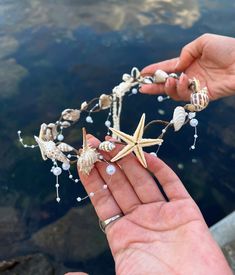 a hand holding a starfish and seashell necklace