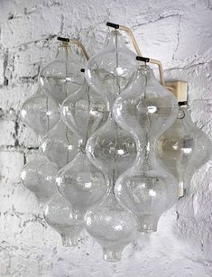 a bunch of glass vases hanging from a light fixture on a brick wall background