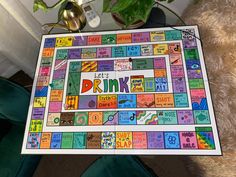 a game board with the words drink on it sitting next to a potted plant