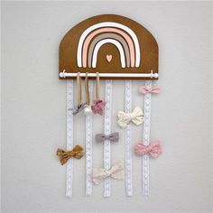 a wooden wall hanging with bow clips and a rainbow decoration on the top of it