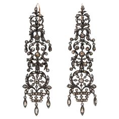 A striking pair of earrings from the Georgian (ca1750s) era! Crafted in sterling silver, these heavily patinaed earrings have an elaborate closed-back design encrusted with glinting Rose Cut diamonds weighing an approximate collective 2ctw. The ornate floral design is comprised of swirling leaves and potted flowers with marquise-shaped dangling details. 18kt yellow gold European wires secure the pair to the wearer's ears, and they frame the face beautifully. This magnificent pair would look phen Luxury Ceremonial Earrings With Intricate Design, Luxury Ceremonial Pierced Earrings, Ornate Chandelier Earrings For Formal Occasions, Victorian Silver Ceremonial Earrings, Victorian Silver Earrings For Ceremonial Occasions, Luxury Silver Baroque Earrings, Elegant Ceremonial Earrings With Oxidized Finish, Ornate Rose Cut Diamond Earrings, Elegant Oxidized Earrings For Ceremonial Occasion