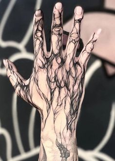 a person's hand with black and white ink on it, holding something in the air