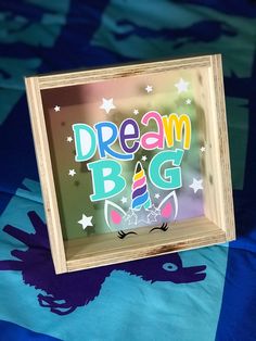 a wooden frame with the words dream bag on it and a unicorn drawn in rainbow colors