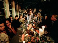 a group of people sitting around a table with candles in front of them on halloween night