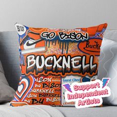 an orange pillow sitting on top of a couch next to a sign that says bucknell