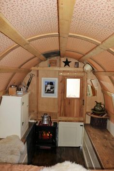 the interior of a tiny home with wood flooring and walls, including a stove top oven