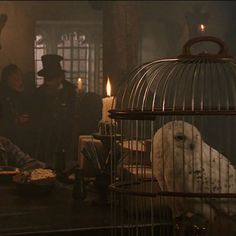 a man sitting at a table in front of a bird cage with candles on it