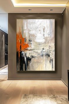 an abstract painting hangs in the corner of a room with wood flooring and beige walls