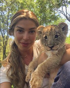 a woman holding a baby lion cub in her arms