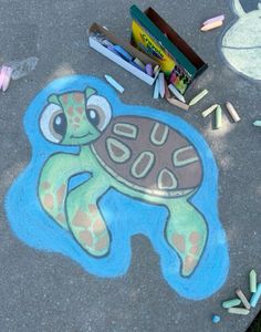 a chalk drawing of a turtle on the ground next to crayons and pencils