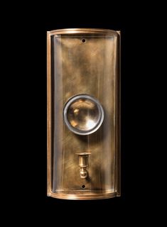 an old fashioned brass wall light with a round glass cover on the front and side