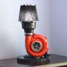 an orange lamp sitting on top of a wooden table next to a black and white wall