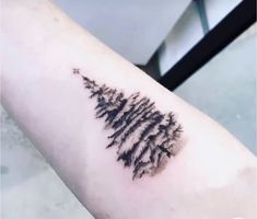 a small pine tree tattoo on the arm