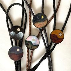 "These are all bolos I offer individually, and have a few in stock. I set this up for larger made-to-order sales. In the order shown, they are desert moon, desert sun, Mars sunset, moon eclipse and moon mountain. These are all made by enameling copper, that is, kiln-firing glass onto a copper base at 1350˚-1600˚F. The suns are fine silver under a layer of clear enamel. These are handcrafted and high quality. No two will be identical. The string tie is a choice of: woven black rayon cord black br Handmade Elegant Bolo Ties For Gift, Handmade Elegant Bolo Ties As A Gift, Artisan Jewelry With Adjustable Length For Gift, Artisan Jewelry With Adjustable Length As Gift, Handmade Gold Bolo Tie For Gift, Handmade Adjustable Enamel Jewelry, Unique Adjustable Bolo Tie For Gift, Unique Adjustable Bolo Ties For Gifts, Unique Handmade Adjustable Bolo Ties