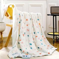 a blanket is laying on the floor in front of a table and chair with a remote control