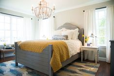 a bedroom with a bed, nightstand and chandelier hanging from it's ceiling