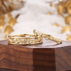 two gold wedding rings sitting on top of a wooden box