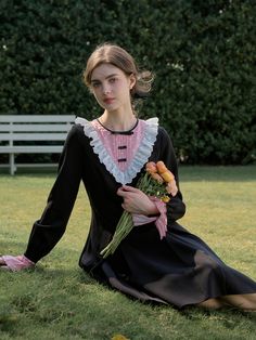 a woman sitting in the grass holding flowers