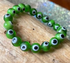 "This a simple and classy evil eye bracelet in bright grass green.  It is believed that the evil eye  protects its owner from harmful energy and negativity.  Generally worn on the left wrist if you need protection over your emotions or personal life and on the right wrist if you need protection over material things such as money.  Because the left side of our body is the one linked to our emotions as it is the side of our hearts and the right side to our brain and the analytical parts of ourselv Green Evil Eye, Material Things, White Bracelet, Christmas Bracelet, White Bracelets, Eye Bracelet, Grass Green, Evil Eye Bracelet, Green Grass