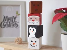 three wooden blocks are stacked on top of each other in front of a potted plant