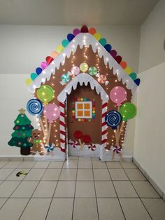 an indoor gingerbread house decorated with balloons and candy canes for the front door