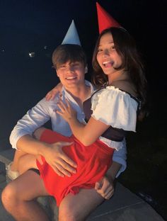 a young man and woman sitting next to each other wearing party hats on their heads