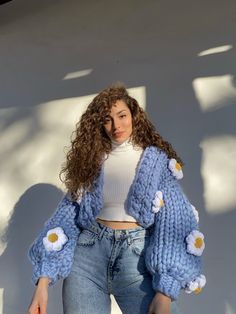 a woman with curly hair wearing jeans and a sweater